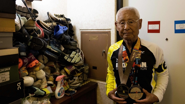 World's oldest Ironman Hiromu Inada, who turns 89 in November, posing for a picture next to a stack of his shoes at his house in Inage , Japan (Getty)