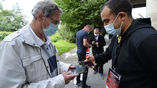 Staff members check supporters' Covid-19 health pass and tickets before the start of the French football match between Stade Rennais Football Club and RC Lens