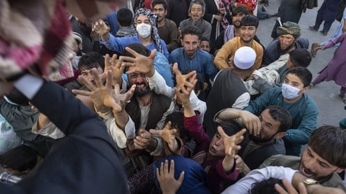 Displaced Afghans reach out for aid from a local Muslim organisation at a makeshift IDP camp in Kabul