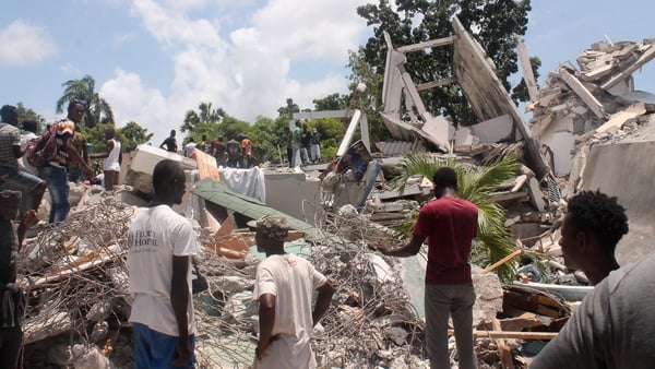 People search through the rubble of what used to be the Manguier Hotel in Les Cayes