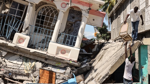 Residents survey a damaged building in Les Cayes, Haiti