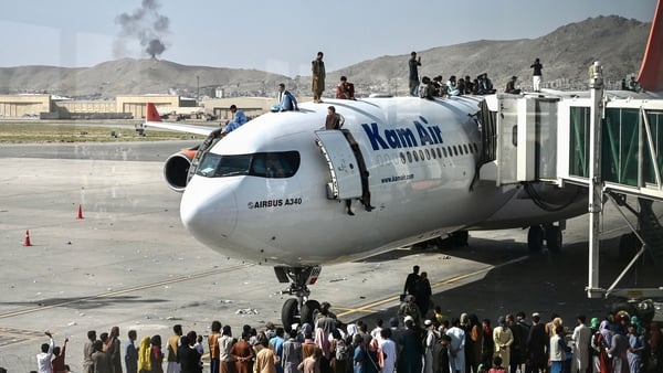 Afghan people climb atop a plane as they wait at Kabul airport