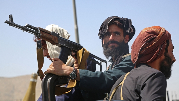 Taliban fighters stand guard in a vehicle along the roadside in Kabul
