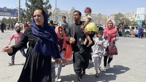 An Afghan family rushes to the Hamid Karzai International Airport