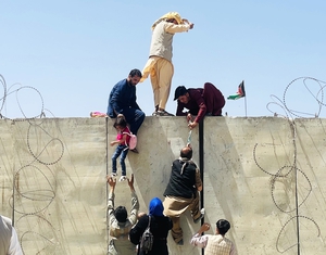 Civilians climb a wall at Hamid Karzai International Airport as they try to flee Kabul