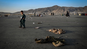 An Afghan child walks near discarded military uniforms as he waits with family to leave the airport