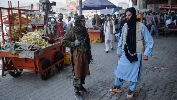 A Taliban fighter stands by a kiosk selling sugarcane juice at a market area, flocked with local Afghan people in Kabul after Taliban seized control of the capital