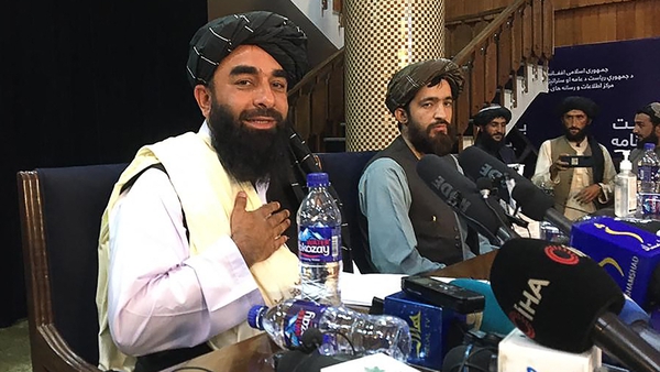 Taliban spokesperson Zabihullah Mujahid (left) gestures as he arrives to hold the first press conference in Kabul
