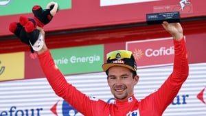 Primoz Roglic celebrates on the podium wearing the overall leader's red jersey after the sixth stage