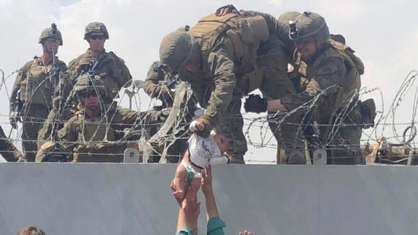 A US soldier is handed a baby at Kabul Airport as people try to flee Afghanistan
