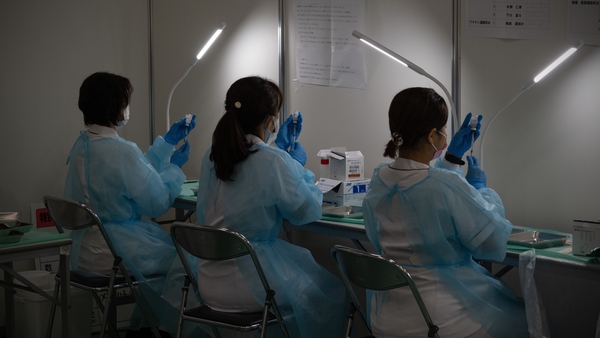 Medical staff prepare syringes of the Moderna vaccine at a vaccination centre in Tokyo
