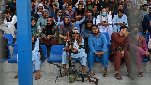 A Taliban fighter keeps watch as spectators watch the Twenty20 cricket trial match being played between two Afghan teams - 'Peace Defenders' and 'Peace Heroes' - at Kabul International Cricket Stadium today
