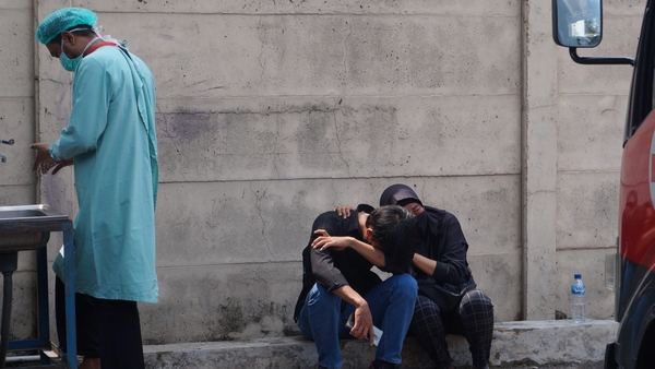 Family members of one of the victims sit outside the prison