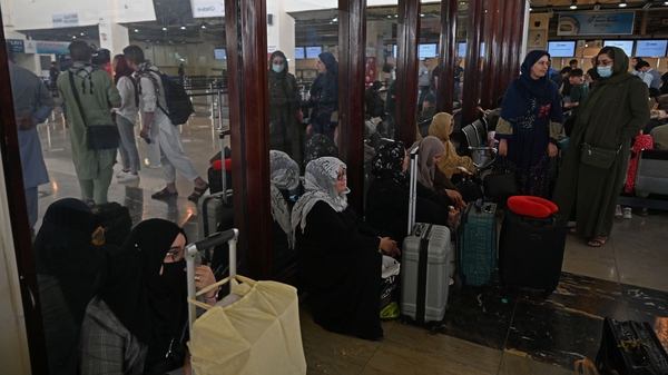 Passengers sit inside the departure terminal at the airport in Kabul