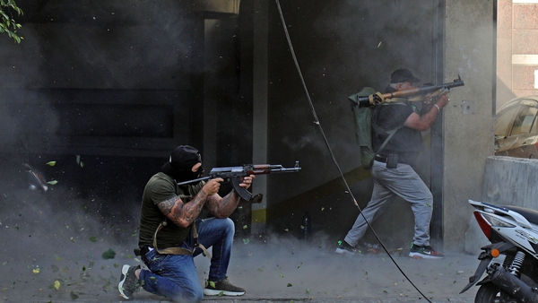 Fighters from Hezbollah and Amal movements take aim a Kalashnikov assault rifle and a rocket-propelled grenade launcher in Beirut