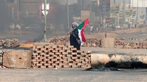 A man carrying a Sudanese national flag walks by roadblocks set up by protesters in the capital Khartoum