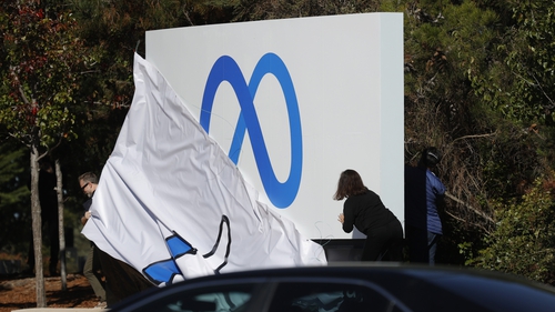 Facebook employees unveil a new logo and the name 'Meta' on the sign in front of Facebook headquarters in California