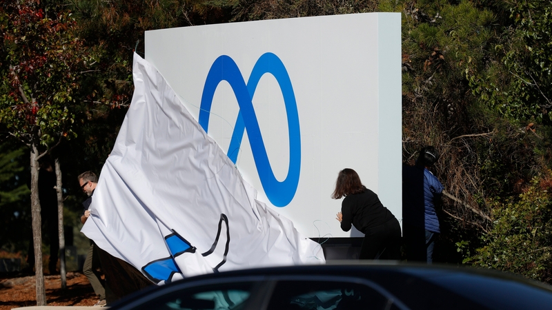 Facebook employees unveil a new logo and the name 'Meta' on the sign in front of Facebook headquarters in California