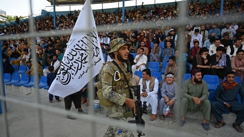 A Taliban fighter patrols as an all-male crowd watches the Twenty20 trial match between the Peace Defenders and the Peace Heroes at Kabul International Cricket Stadium in September