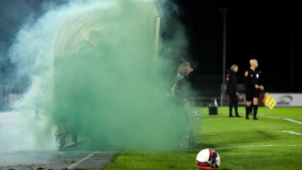 Shamrock Rovers physiotherapist Tony McCarthy attempts to remove a flare from the dugout area