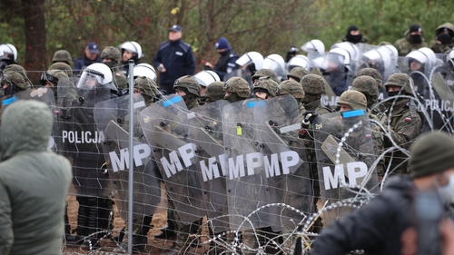 Poland's law enforcement officers watch migrants at the Belarusian-Polish border