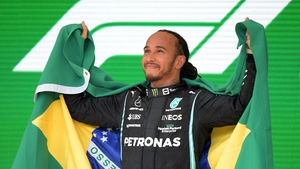 Lewis Hamilton celebrates on the podium with the Brazilian flag
