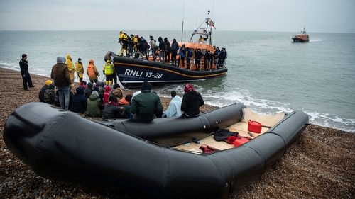 Migrants sit beside a boat used to cross the English Channel last week