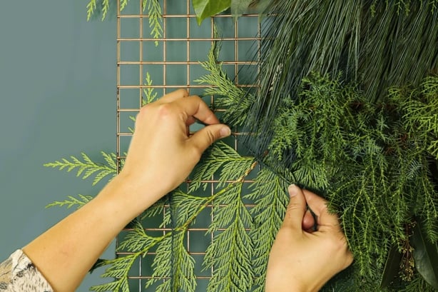 Attaching foliage to a metal grid to create a floral tapestry (Dobbies Garden Centres/PA)