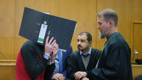Taha Al-Jumailly (L) hides his face as speaks with his legal team in court