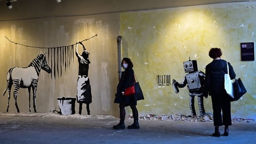 Visitors look at Banksy's murals during a preview of the 'World of Banksy' exhibition