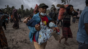 A man carries a child as he and other people flee the area around Mount Semeru