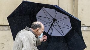 A man struggles with his umbrella in Belfast, which is also under a Yellow wind warning