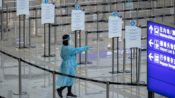 A health worker directs travellers to the arrival hall before being dispatched to quarantine hotels at Hong Kong International Airport