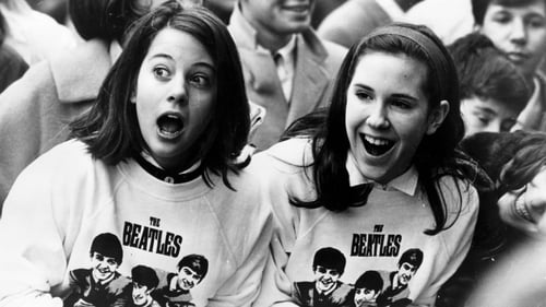 10th February 1964: Two excited girls in Beatles sweatshirts, amongst a crowd of fans in New York
