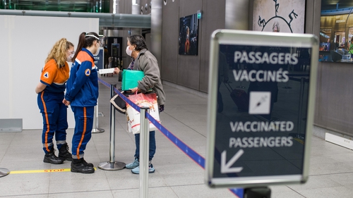 Members of the civil protection ambulance service check the vaccination status of an arriving passenger at Paris-Charles de Gaulle airport