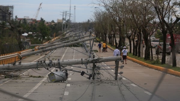 Residents walk past downed electric pylons in Talisay town, Cebu province