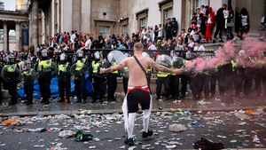 A fan waves a smoke bomb in front of a line of police officers monitoring England supporters at Trafalgar Square