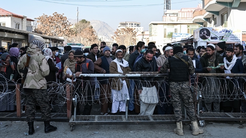 A Taliban fighter (right) inspects documents of people queuing to enter the passport office in Kabul today