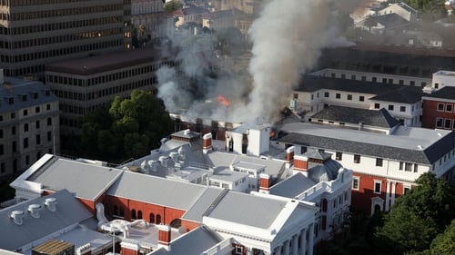 A plume of smoke rises above the parliament building in Cape Town