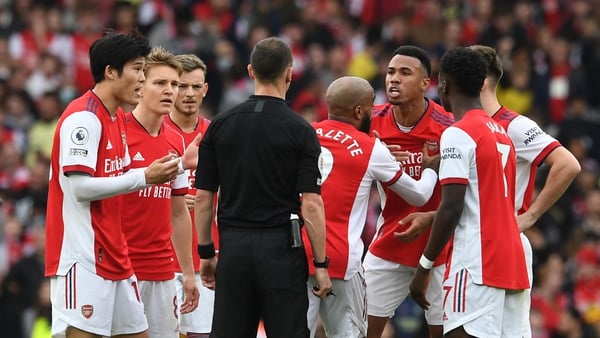 Arsenal players, including Gabriel Magalhaes (third from right), surround referee Stuart Atwell in their loss to Man City