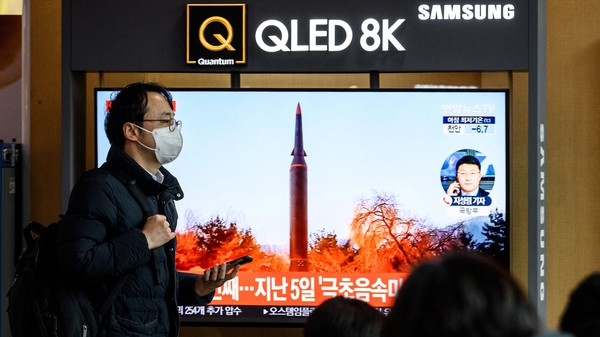 A man walks past a television screen showing a news broadcast with file footage of a North Korean missile test, at a railway station in Seoul