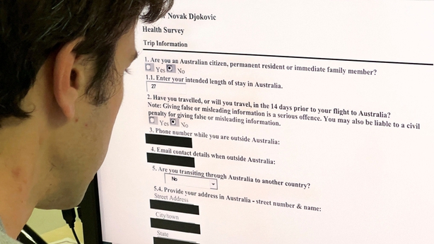 A journalist looks at a computer screen in Hong Kong on January 11, 2022 showing a copy of Serbian tennis champion Novak Djokovic's health survey submitted during his Australian visa application process. - Djokovic was released from detention in Melbourne on January 10, where he had arrived ahead of the Australian Open, following a ruling that overturned the cancellation of his Australian visa over his Covid-19 vaccination status. (Photo by Mladen ANTONOV / AFP) (Photo by MLADEN ANTONOV/AFP via Getty Images)