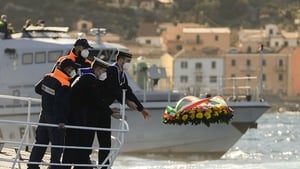 Port authority and coast guard members throw a wreath in the water where the cruise ship ran aground