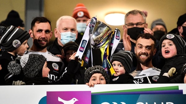 Kilcoo joint-captains Aidan Branagan, left, and Conor Laverty lift the trophy with their children
