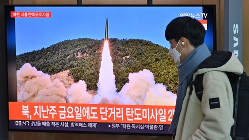 A man walks past a television screen today showing a news broadcast with file footage of a North Korean missile test