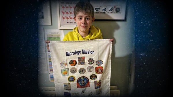 Brendan Brown holding a picture of all 24 mission patches