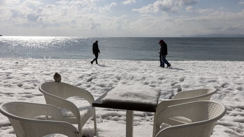 A table and chairs covered in snow on a terrace on the beach in Alimos, a suburb of Athens