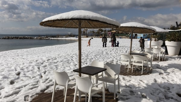 Heavy snowfall covers a beach and sun parasols in Athens