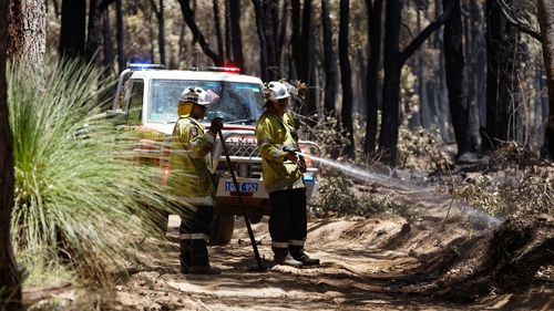 Firefighters conduct mop up operations after a bushfire was extinguished in the suburbs of Perth