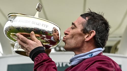 Davy Russell gives the Irish Gold Cup a kiss after prevailing aboard long-shot Conflated